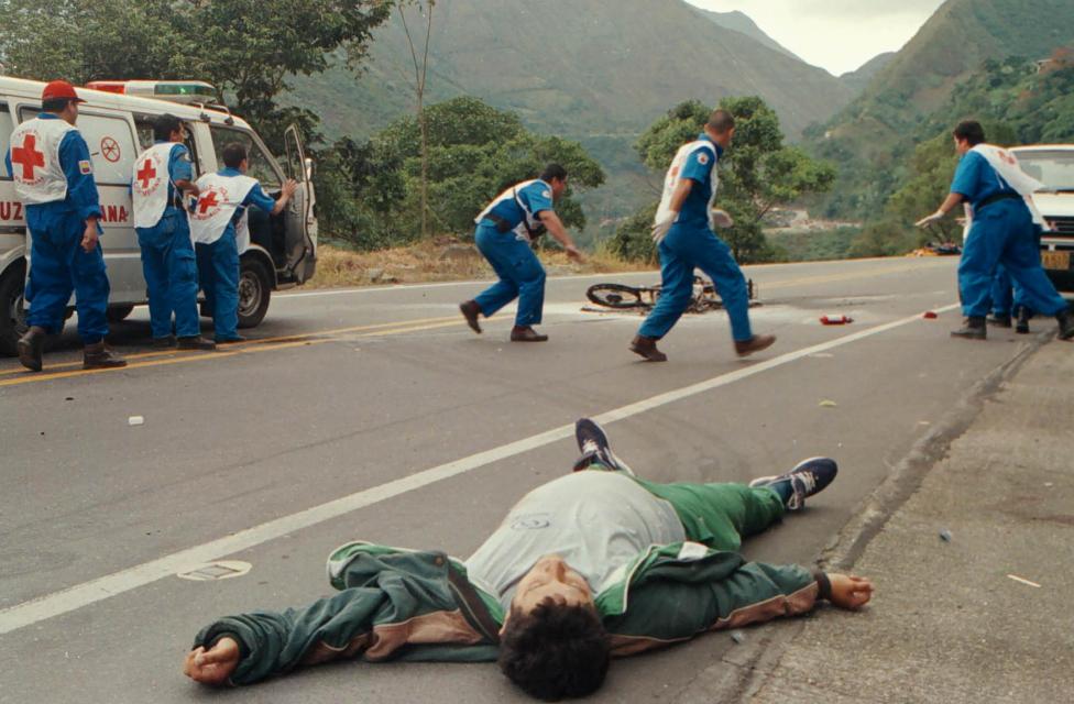 A dead civilian lies in the road as Red Cross workers run for protection after an attack in Guayabetal, January 2000.
