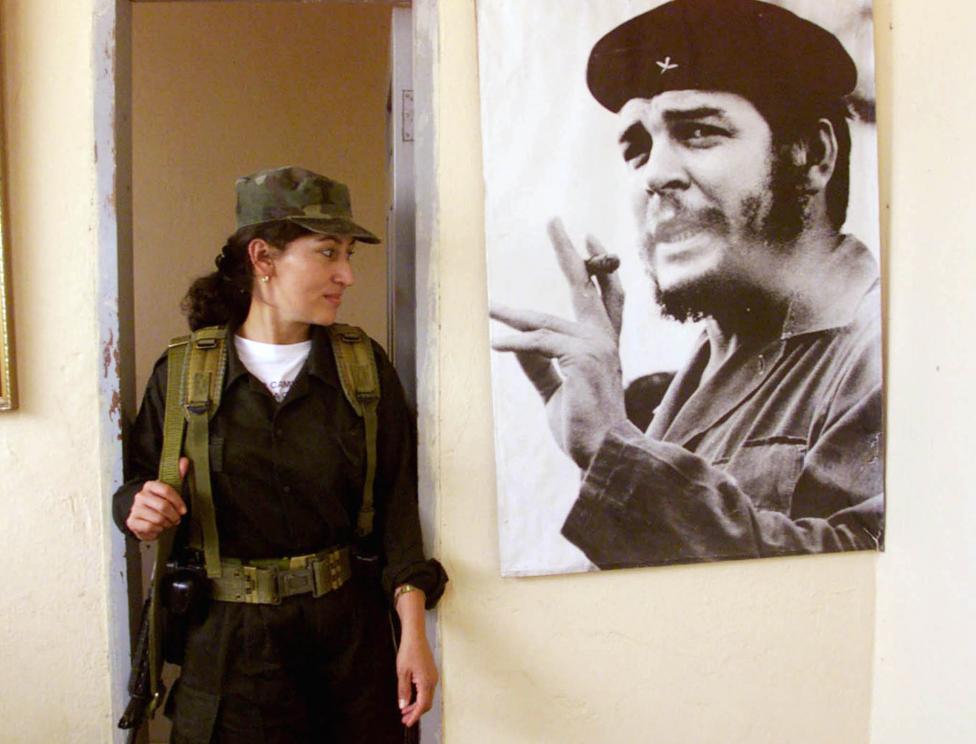 A FARC rebel looks at a photo of legendary guerrilla leader Ernesto 