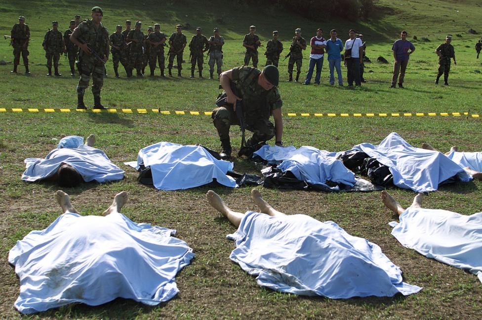 A Colombian soldier looks at the bodies of FARC rebels killed in combat in La Plata, Huila province, July 2002.