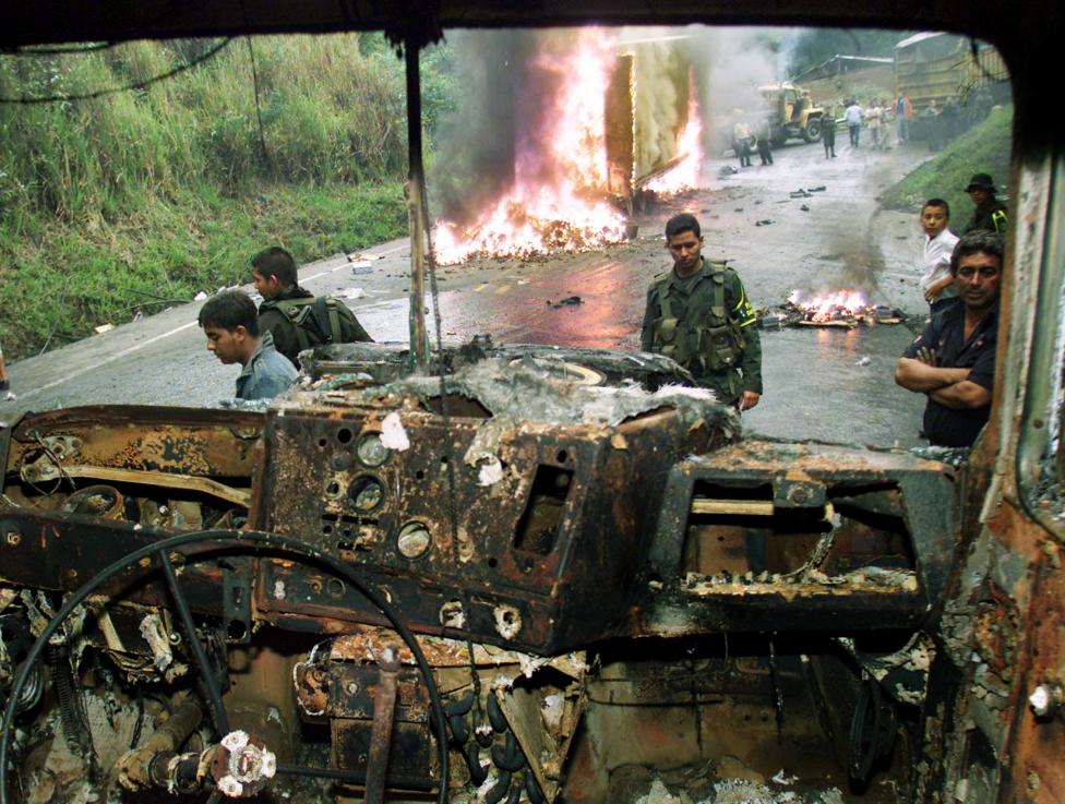 Colombian police and peasants look at a truck burned by FARC rebels in Dagua, Valle province, April 2003.