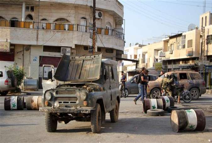 Militants from the Jund al-Aqsa terrorist group walk near an abandoned Syrian army vehicle in the northern Syrian town of Tayyibat al-Imam, northwest of Hama on August 31, 2016.