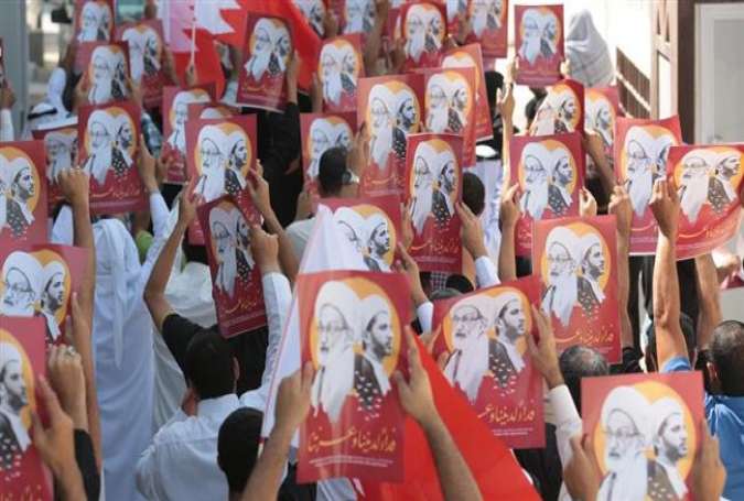 Bahraini demonstrators attend a protest rally against the revocation of the citizenship of top Bahraini Shia cleric Sheikh Isa Qassim (portrait), near his house in the village of Diraz, west of Manama, on October 14, 2016.