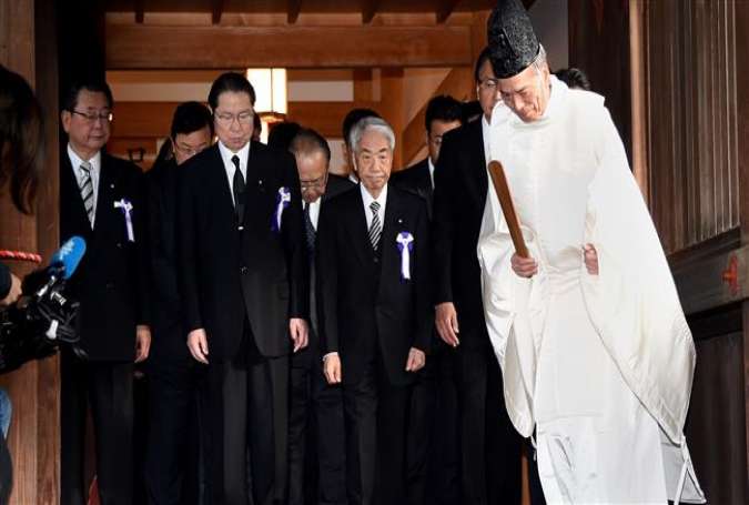 A Shinto priest (R) leads a pack of lawmakers at Yasukuni Shrine in Tokyo on October 18, 2016.