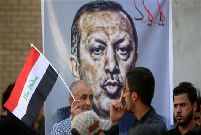 Iraqis stand in front of a banner bearing a portrait of Turkish President Recep Tayyip Erdogan during a demonstration to demand the withdrawal of Turkish troops from Iraq, outside the Turkish Embassy in Baghdad, October 8, 2016.
