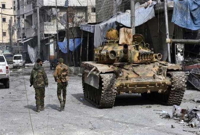 Syrian soldiers pass by a tank in an area in the east of Syria’s second city of Aleppo, December 12, 2016.