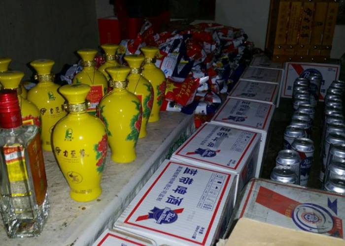 گلگت، پولیس اہلکار چینی شہری سے برآمد شدہ شراب میڈیا کو دکھاتے ہوئے