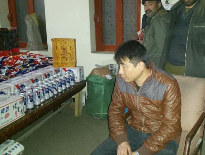 گلگت، پولیس اہلکار چینی شہری سے برآمد شدہ شراب میڈیا کو دکھاتے ہوئے