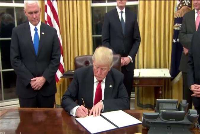 US President Donald Trump signs an executive order against Obamacare at the Resolute Desk in the Oval Office on Friday, January 20, 2017.