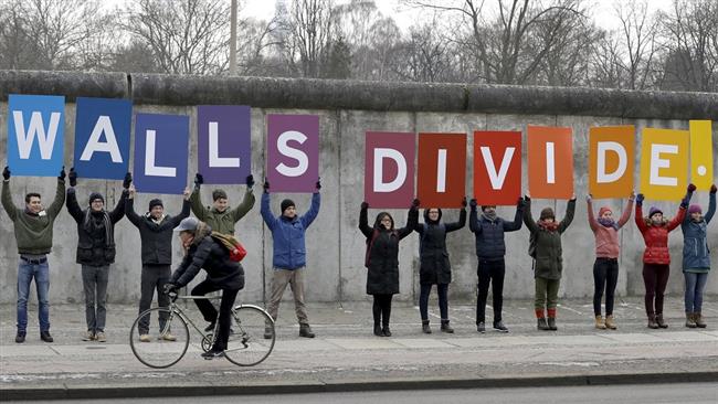 Greenpeace protesters stage an anti-Trump demo at Germany’s Berlin Wall memorial on January 20, 2017, holding placards that read, “Mr President, walls divide. Build bridges!”
