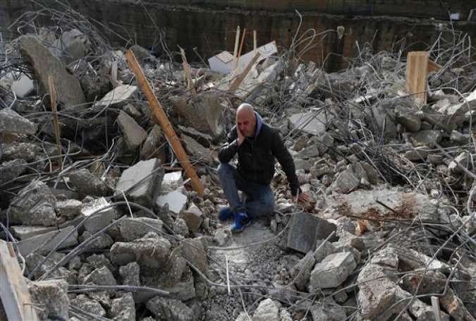 A Palestinian man sits amid the rubble of a house that was demolished by Israeli military bulldozers in the East Jerusalem al-Quds neighborhood of Beit Hanina on January 4, 2017.