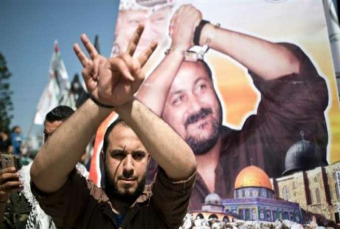 A Palestinian man gestures in front of a poster bearing the portrait of Fatah leader Marwan Barghouti, during a rally marking Palestinian Prisoner Day in Gaza City on April 17, 2016. (Photo by AFP)