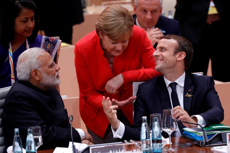French President Emmanuel Macron talks to German Chancellor Angela Merkel as India's Prime Minister Narendra Modi listens.