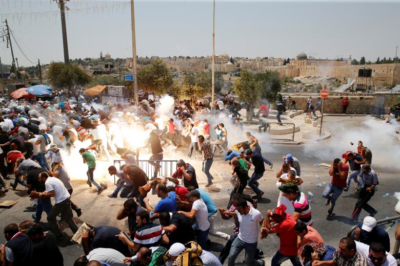 Palestinians react following tear gas that was shot by Israeli forces after Friday prayer on a street outside Jerusalem