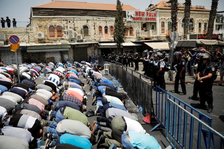 Palestinians pray on a street near a road block outside Jerusalem