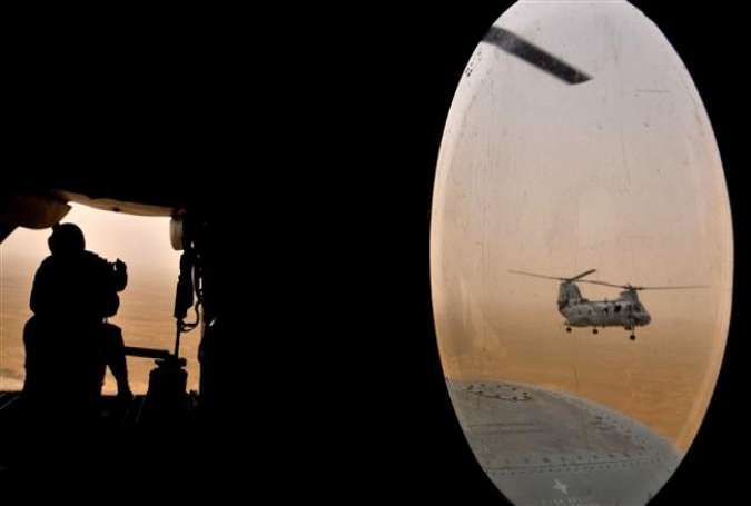 This AFP file photo taken on May 3, 2008 shows a US soldier (L) sitting in the rear of a Marine Chinook helicopter while flying over Camp Bastion in Helmand province, southwest of Kabul. (Photo by AFP)