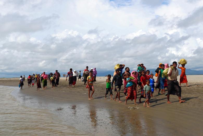 Rohingya refugees walk on the shore after crossing the Bangladesh-Myanmar border by boat through the Bay of Bengal in Shah Porir Dwip, Bangladesh.