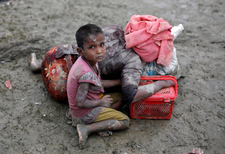 A Rohingya refugee girl sits next to her mother who rests after crossing the Bangladesh-Myanmar border, in Teknaf, Bangladesh.