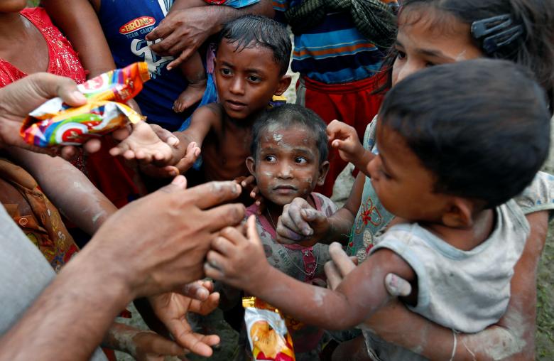 Rohingya refugees stretch their hands for food after crossing the Bangladesh-Myanmar border, in Teknaf, Bangladesh.