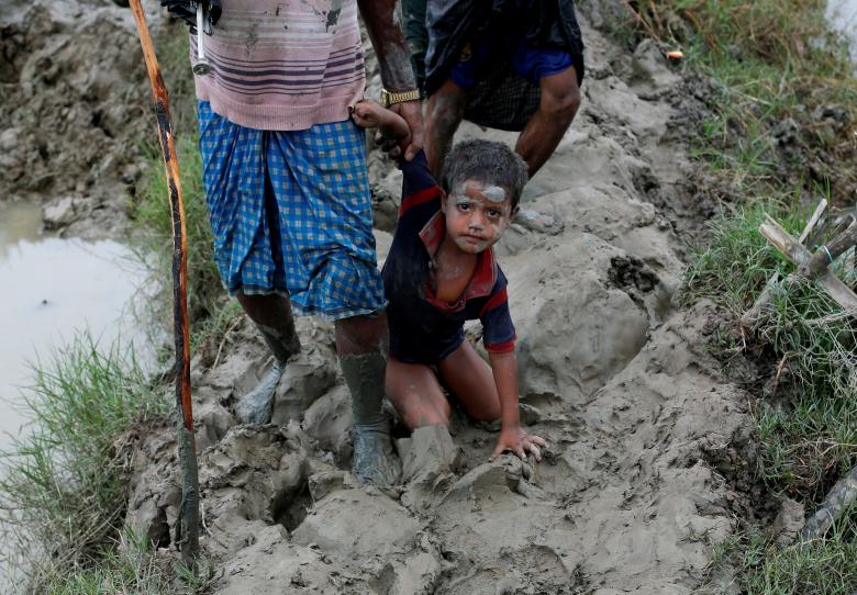 A Rohingya refugees boy falls as he walks on a muddy path after crossing the Bangladesh-Myanmar border, in Teknaf, Bangladesh.