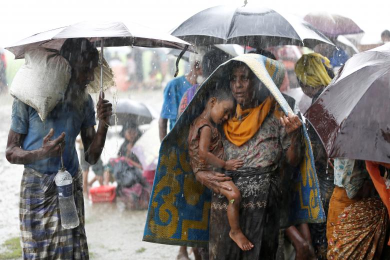 Rohingya refugees stands in an open place during heavy rain, as they are hold by Border Guard Bangladesh (BGB) after illegally crossing the border, in Teknaf, Bangladesh.