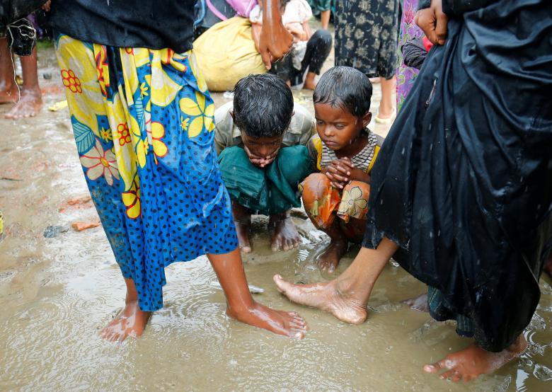 Children among Rohingya refugee people sit on the mud during heavy rain, as they are hold by Border Guard Bangladesh (BGB) after illegally crossing the border, in Teknaf, Bangladesh.