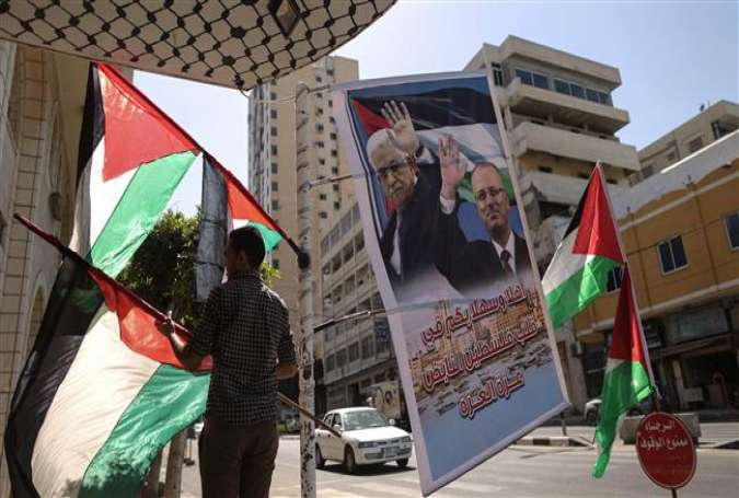 A Palestinian shop owner displays national flags and a poster bearing the portraits of Palestinian Prime Minister Rami Hamdallah and President Mahmoud Abbas on October 1, 2017, in the Gaza Strip. (Photo by AFP)