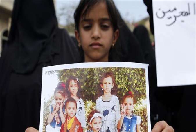 The photo taken in the Yemeni capital, Sana’a, on August 26, 2017 shows a Yemeni child who carries a poster of her family members killed in a Saudi-led airstrike. (By AFP)