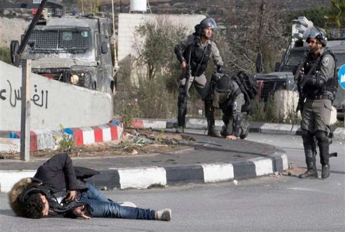 A Palestinian man clutches his stomach after being shot by Israeli soldiers.jpg
