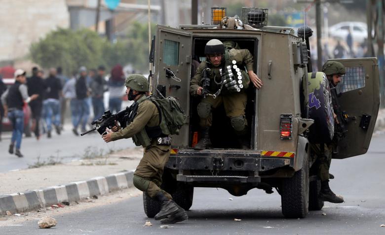 Israeli soldiers get out of a vehicle during clashes with Palestinian demonstrators at a protest as Palestinians call for a 