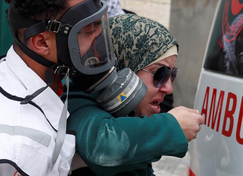 A medic helps a Palestinian woman who is affected by teargas fired by Israeli forces near Qalandia checkpoint near the West Bank city of Ramallah, December 20.