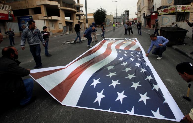 Palestinian demonstrators place on the ground a representation of a U.S. flag during a protest in the West Bank city of Bethlehem December 20.