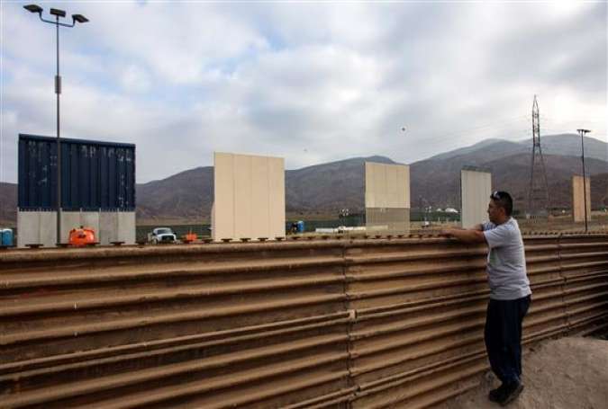 A man watches across the border from Tijuana, Mexico, to prototypes of US President Donald Trump