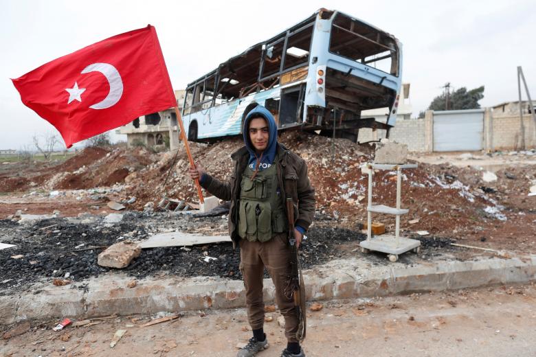 A Turkey-backed Free Syrian Army fighter holds a makeshift Turkish flag as he patrols on a road near Azaz, Syria.