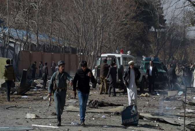 This file photo, taken on January 27, 2018, shows Afghan volunteers and policemen carrying injured men to an ambulance at the scene of a car bomb that exploded in front of the old Interior Ministry building in Kabul. (By AFP)