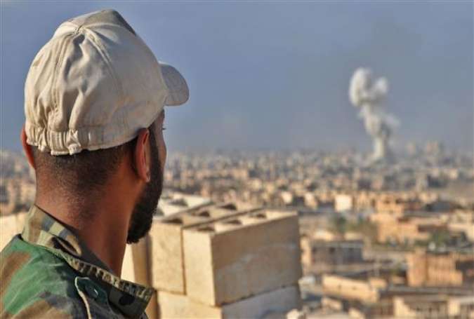 A member of government-allied Syrian forces watches as smoke rises from buildings following an airstrike against Daesh in the eastern city of Dayr al-Zawr, October 31, 2017. (Photo by AFP)