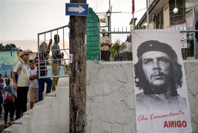 People line up as a banner depicting revolutionary leader Ernesto 
