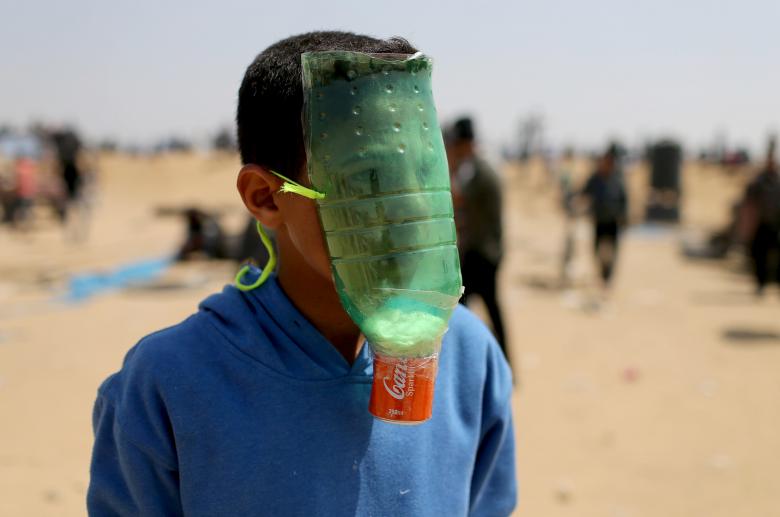A Palestinian protects himself from inhaling tear gas at the Israel-Gaza border during a protest demanding the right to return to their homeland, in the southern Gaza Strip April 6, 2018.