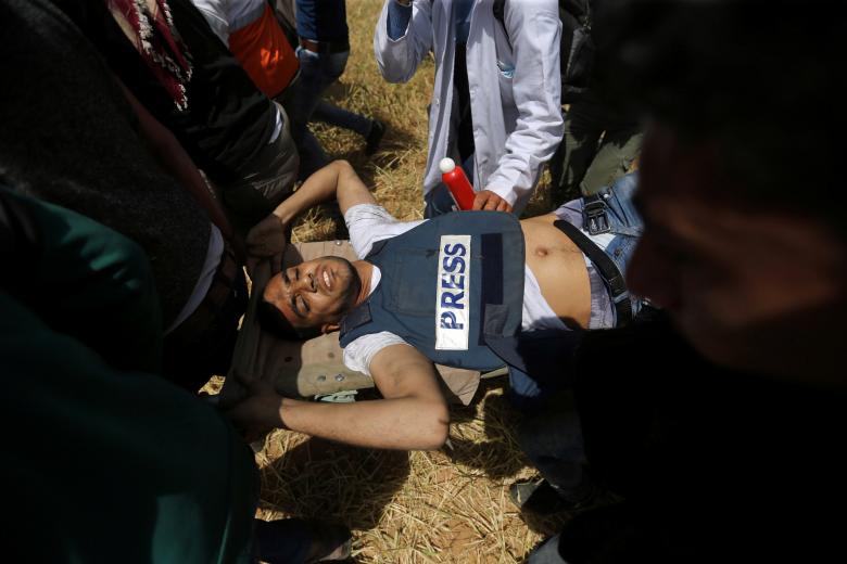 Palestinians evacuate a wounded journalist during clashes with Israeli troops at the Israel-Gaza border at a protest demanding the right to return to their homeland, in the southern Gaza Strip April 6, 2018.