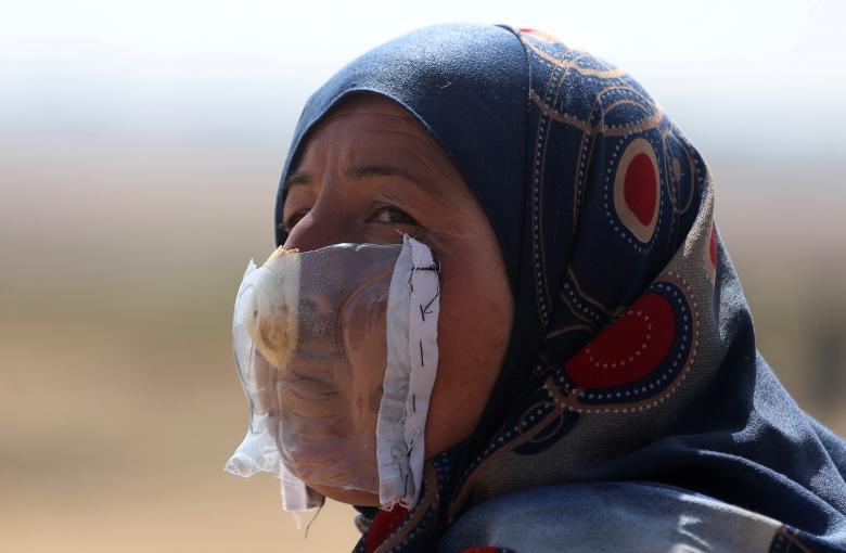 A Palestinian woman protects herself from inhaling tear gas with the help of onion at the Israel-Gaza border during a protest demanding the right to return to their homeland, in the southern Gaza Strip April 6, 2018.