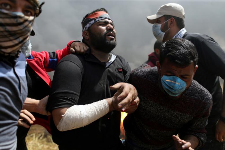A wounded Palestinian demonstrator is helped during clashes with Israeli troops at the Israel-Gaza border at a protest demanding the right to return to their homeland, in the southern Gaza Strip April 6, 2018.