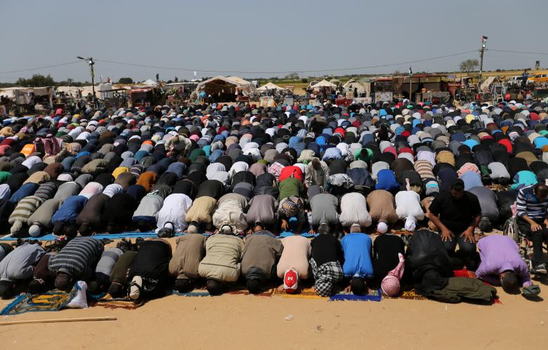 Palestinians perform Friday prayers during a protest demanding the right to return to their homeland, at the Israel-Gaza border in the southern Gaza Strip April 6, 2018.