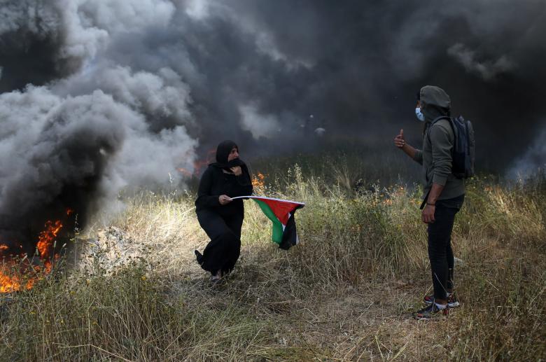 A woman holds a Palestinian flag during clashes with Israeli troops at the Israel-Gaza border at a protest demanding the right to return to their homeland, in the southern Gaza Strip April 6, 2018.