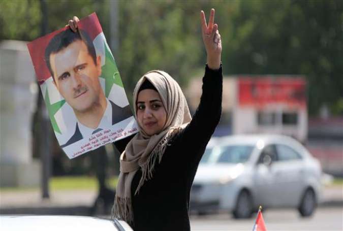 A Syrian woman carries the portrait of President Bashar al-Assad at the Umayyad Square in Damascus on April 14, 2018, during a protest against strikes by the United States, Britain and France. (Photo by AFP)