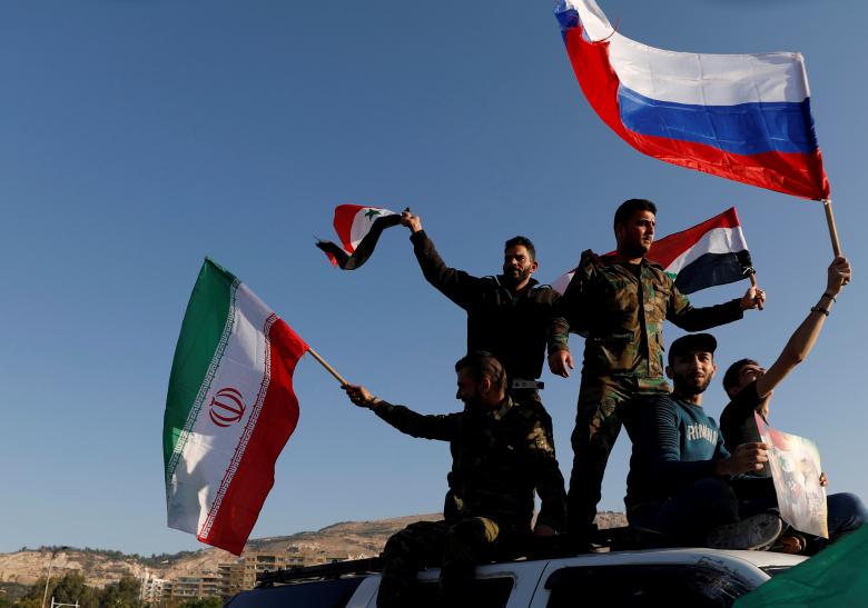 Syrians wave Iranian, Russian and Syrian flags during a protest against U.S.-led air strikes in Damascus, Syria April 14, 2018.