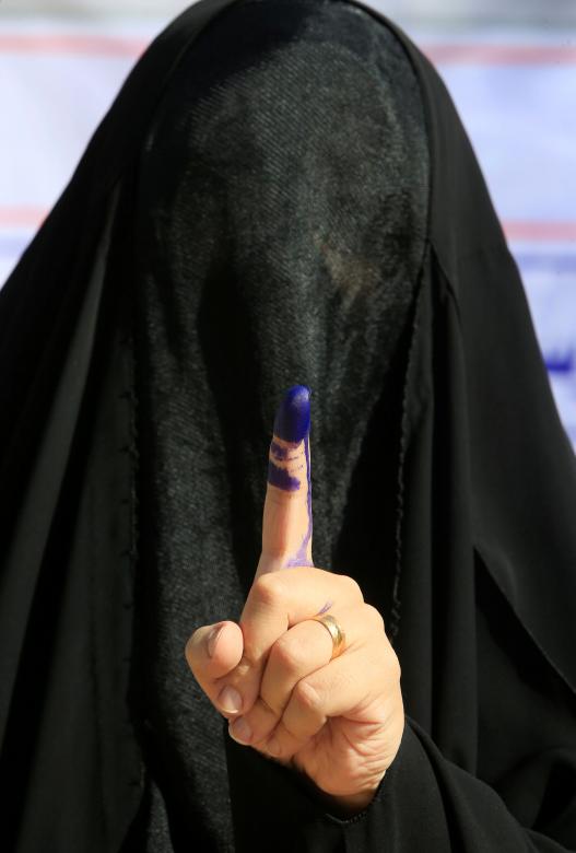 A female security member shows her ink-stained finger after casting her vote in Najaf.