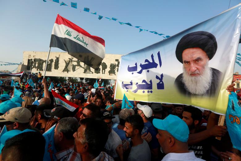Supporters of the Al Sairun Party, which is backed by the Iraqi Shi'ite cleric Moqtada al-Sadr, hold a poster of Iraq's top Shi'ite cleric, Grand Ayatollah Ali al-Sistani, while attending a campaign rally in Baghdad.