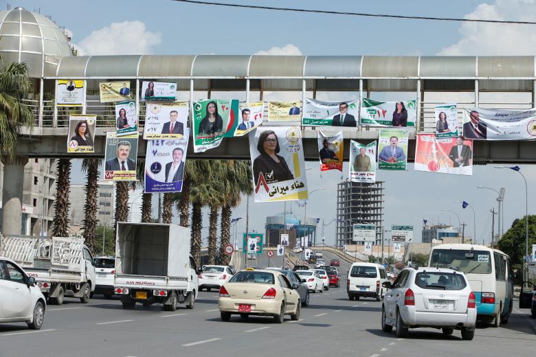 Vehicles drive under campaign posters in Erbil.