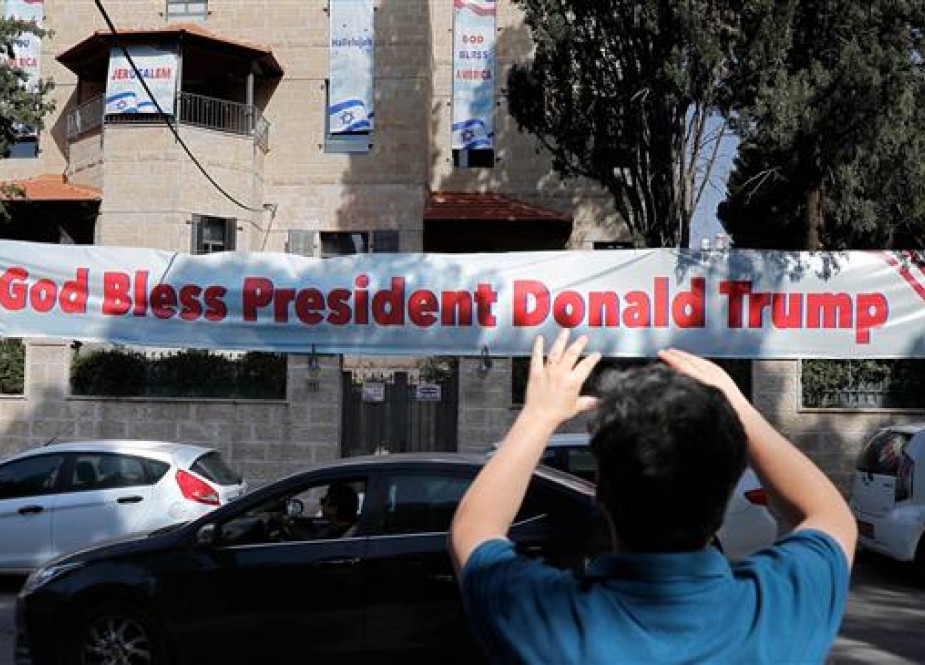 An Israeli man takes a picture on May 11, 2018 of a poster placed near the compound of the US consulate in Jerusalem al-Quds, which will host the new US embassy, as posters praising the US president hang in the street. (Photo by AFP)