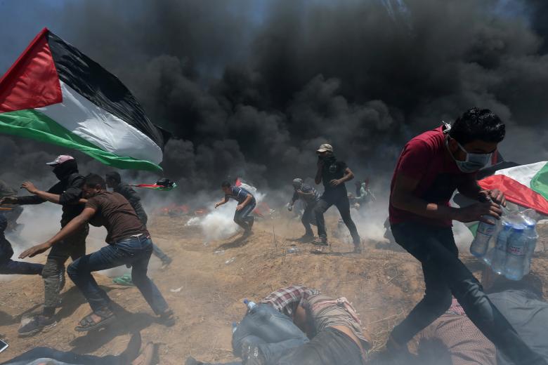 Palestinian demonstrators run for cover from Israeli fire and tear gas during a protest against U.S. embassy move to Jerusalem and ahead of the 70th anniversary of Nakba, at the Israel-Gaza border in the southern Gaza Strip May 14, 2018.