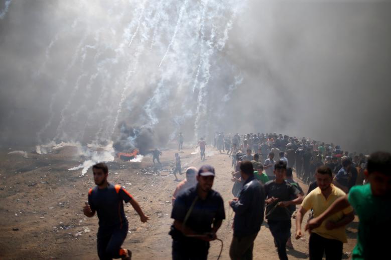 Palestinian demonstrators run from tear gas fired by Israeli troops during a protest against U.S. embassy move to Jerusalem and ahead of the 70th anniversary of Nakba, at the Israel-Gaza border east of Gaza City.